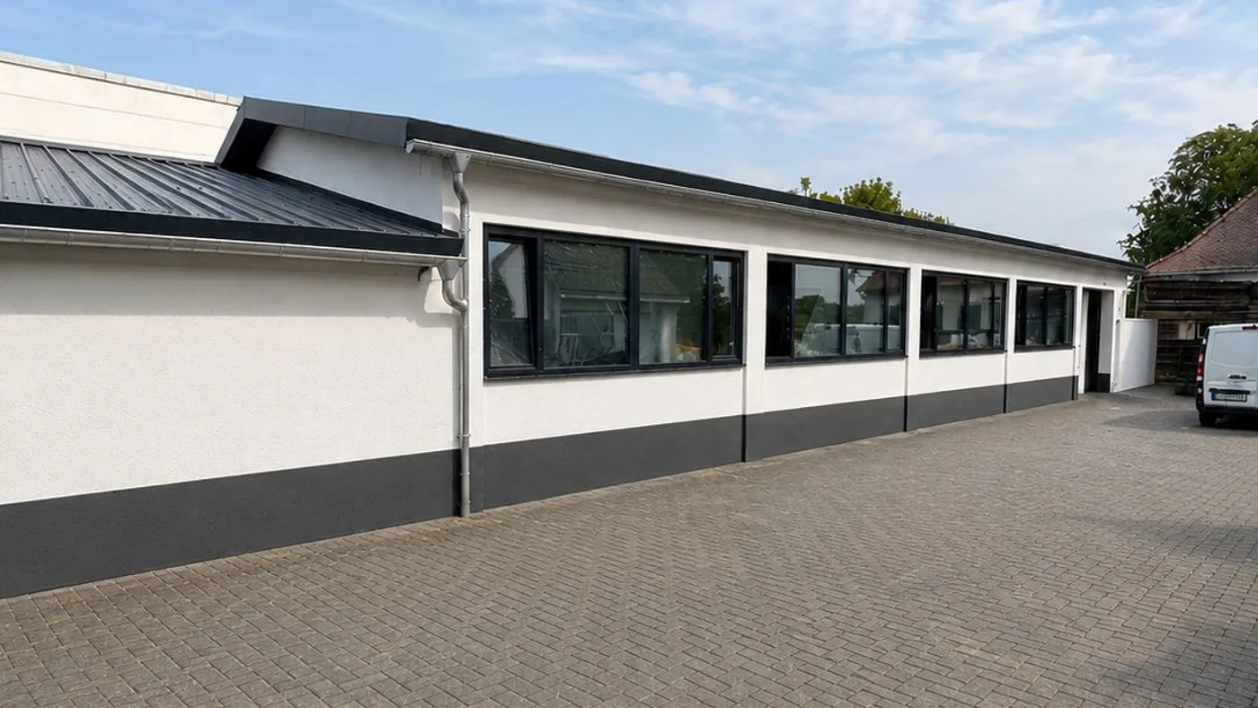 Betriebsgebäude von Koloseus in Karlstein am Main von der Zufahrt aus, mit Fensterband und gepflastertem Hof